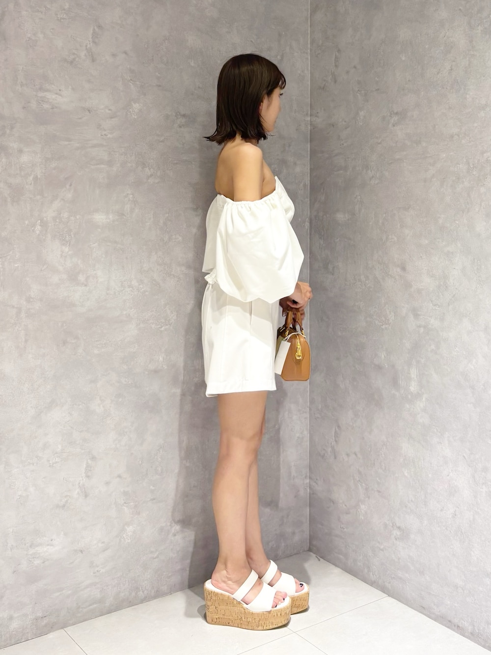 ホワイト系のその他パンツ、ホワイト系のサンダル、ブラウン系のハンドバッグを着用したレディースの夏コーディネートの2枚目の写真