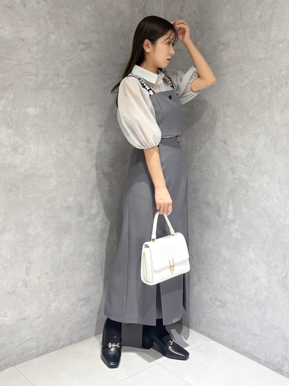 グレー系のスカート、ブラック系のブーツ、ホワイト系のハンドバッグを着用したレディースの春コーディネートの2枚目の写真