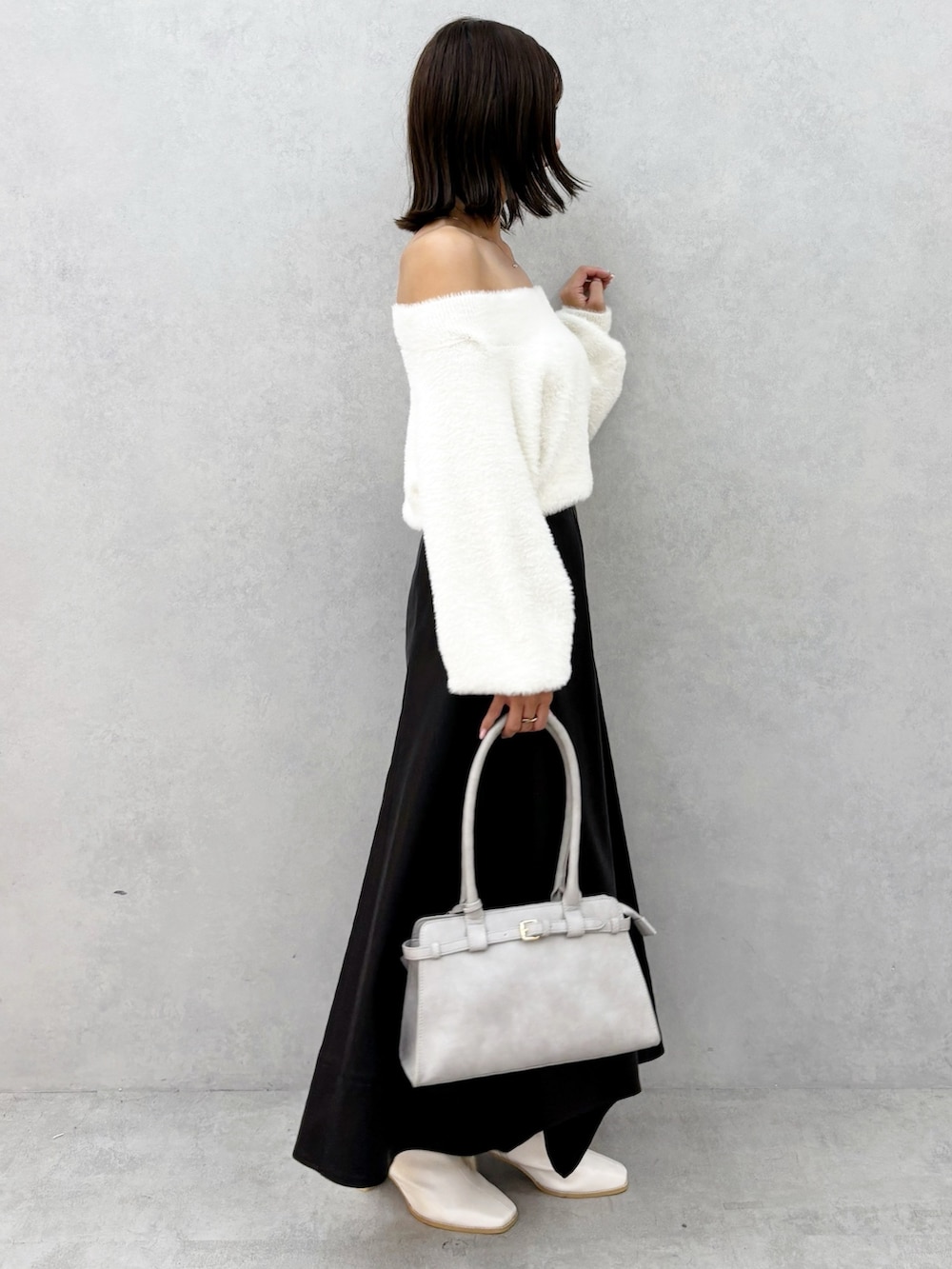 ブラック系のスカート、ホワイト系のブーツ、ホワイト系のニット/セーターを着用したレディースの秋コーディネートの2枚目の写真