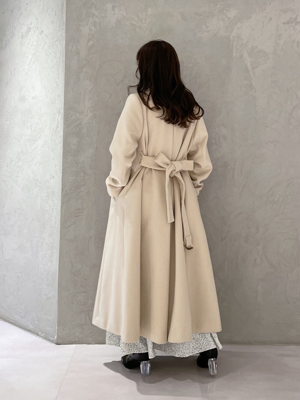 ホワイト系のワンピース、ベージュ系のチェスターコート、ブラック系のブーツを着用したレディースの秋コーディネートの6枚目の写真