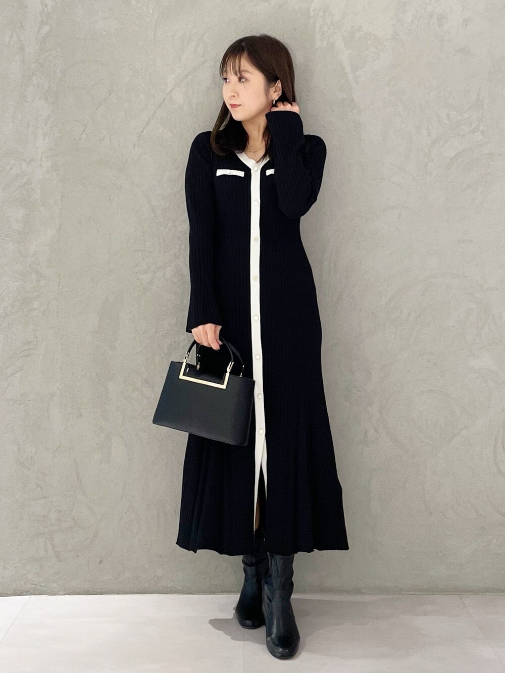 ブラック系のハンドバッグ、ブラック系のブーツ、ブラック系のワンピースを着用したレディースの冬コーディネートの6枚目の写真