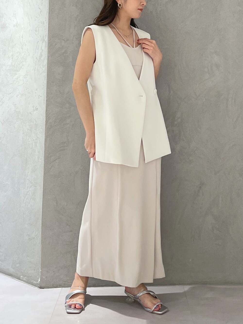 ホワイト系のワンピース、シルバー系のサンダル、ホワイト系のベストを着用したレディースの春コーディネートの2枚目の写真