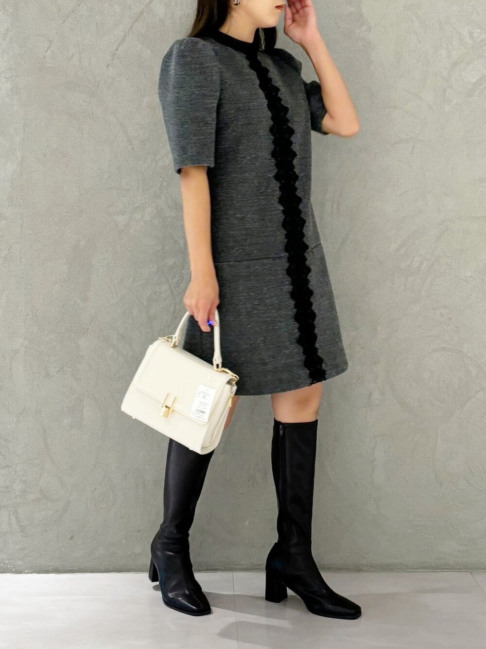 ブラック系のブーツ、ホワイト系のショルダーバッグ、グレー系のワンピースを着用したレディースの秋コーディネートの5枚目の写真