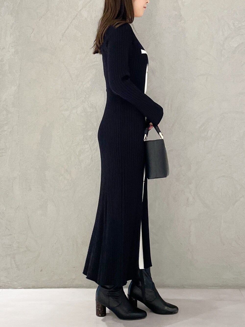 ブラック系のハンドバッグ、ブラック系のブーツ、ブラック系のワンピースを着用したレディースの冬コーディネートの4枚目の写真