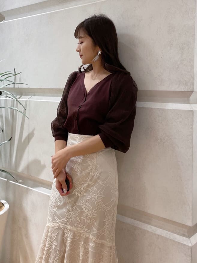 ベージュ系のショルダーバッグ、ブラウン系のカーディガン/ボレロ、ホワイト系のスカートを着用したレディースの冬コーディネートの4枚目の写真