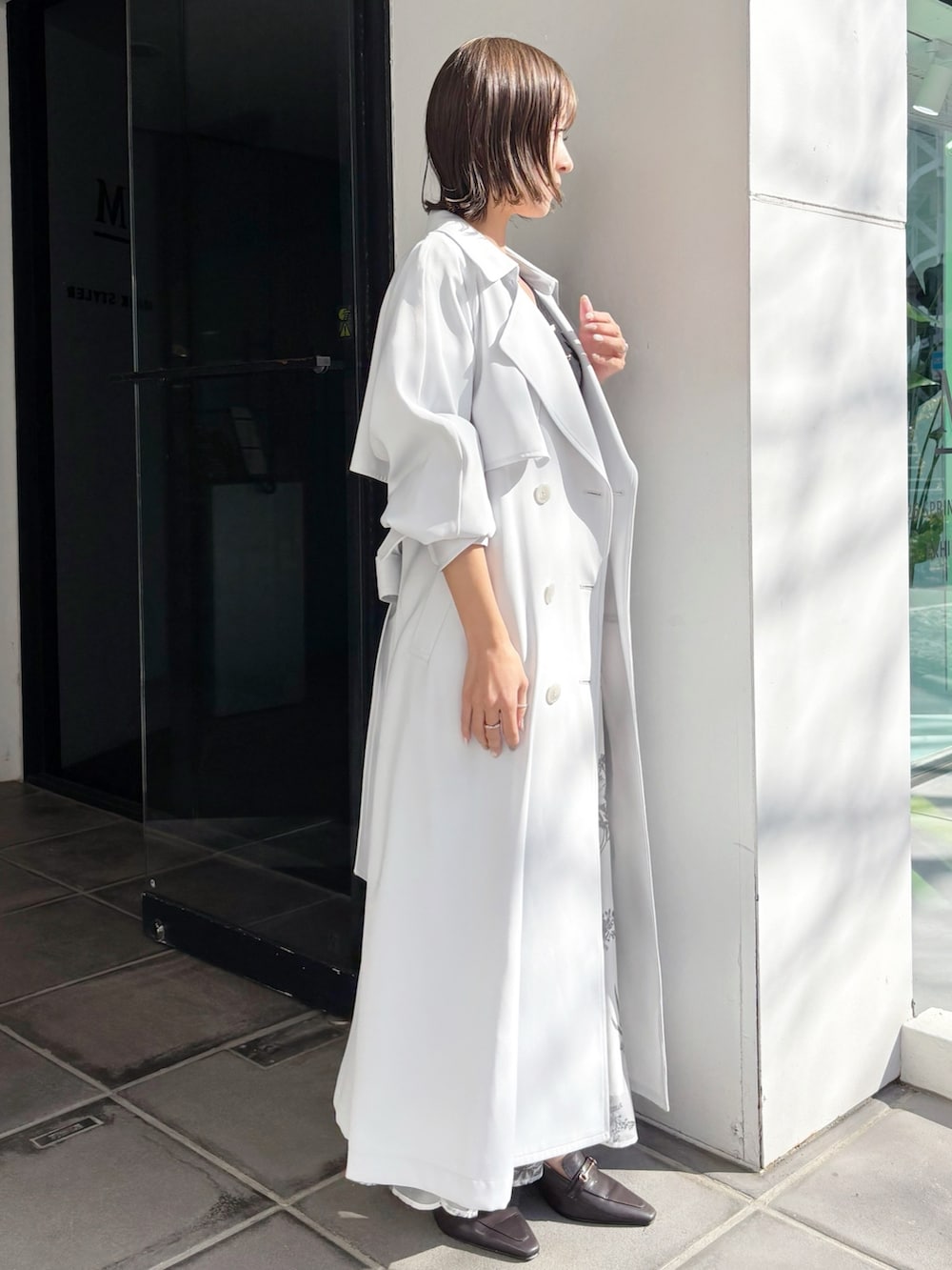 ブラック系のワンピース、ブラウン系のパンプス、ブルー系のトレンチコートを着用したレディースの春コーディネートの5枚目の写真