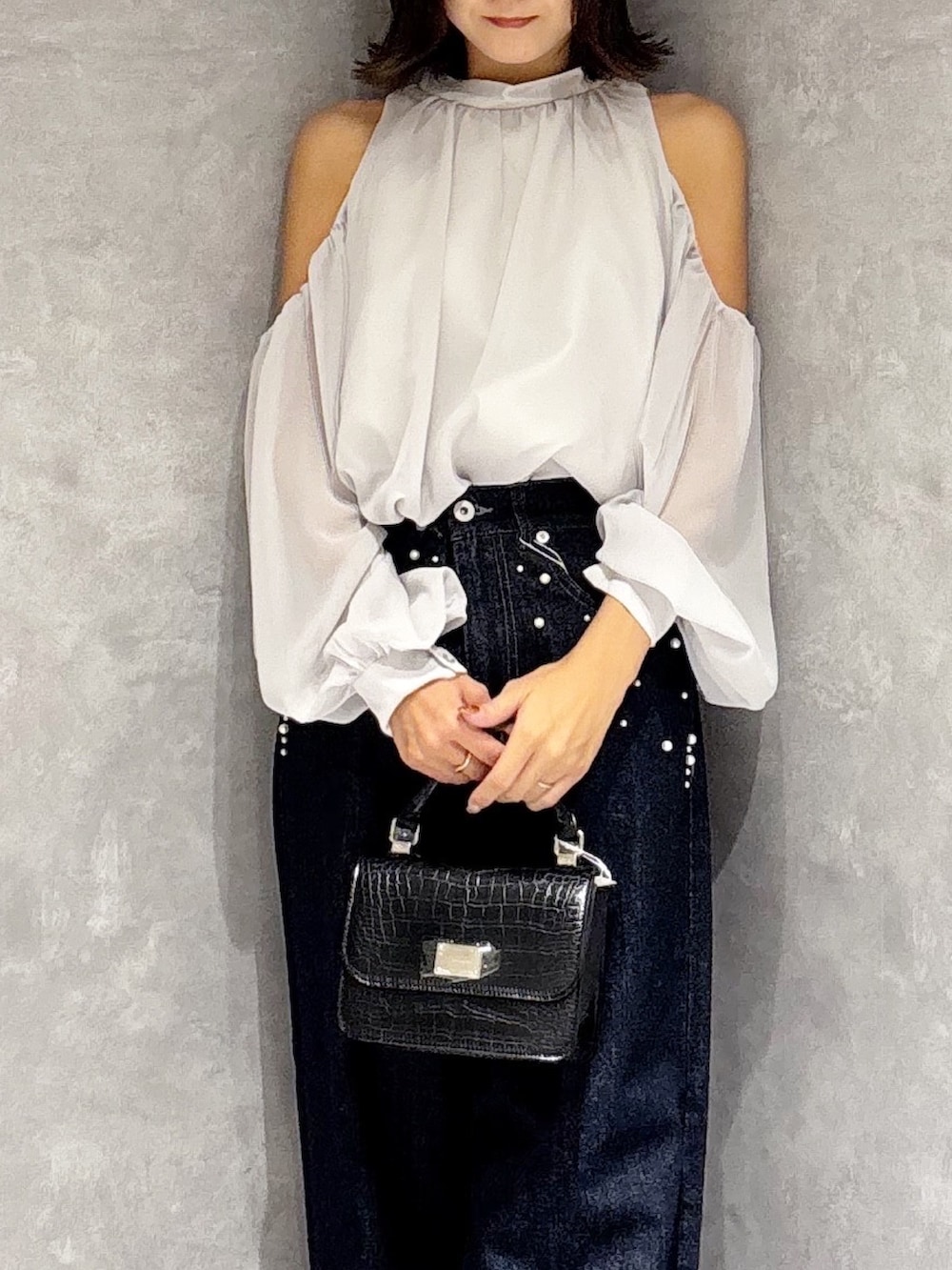 ブルー系のデニムパンツ、ブラック系のブーツ、ブラック系のハンドバッグを着用したレディースの秋コーディネートの6枚目の写真