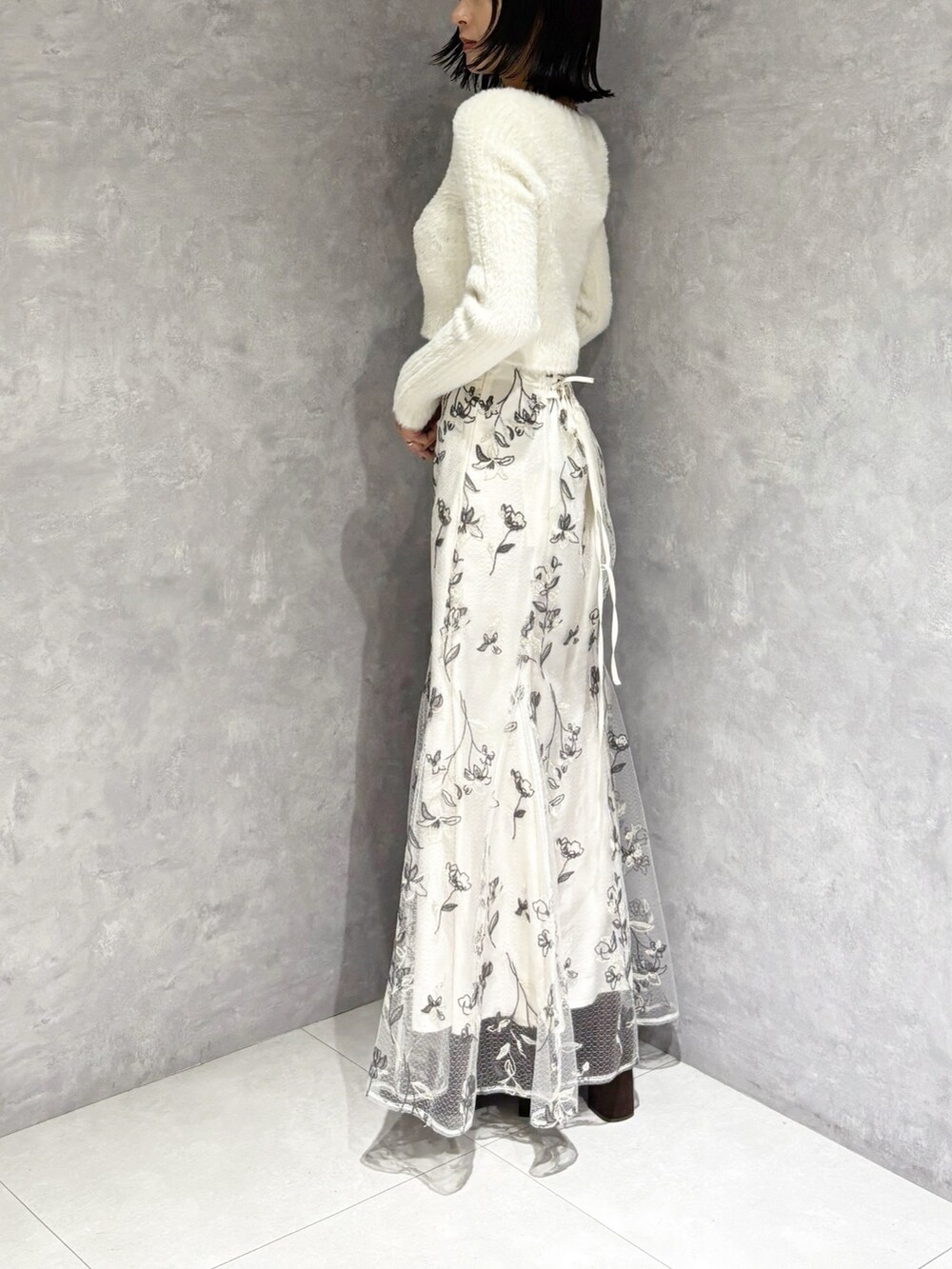 ホワイト系のスカート、ブラウン系のブーツ、ホワイト系のニット/セーターを着用したレディースの秋コーディネートの5枚目の写真