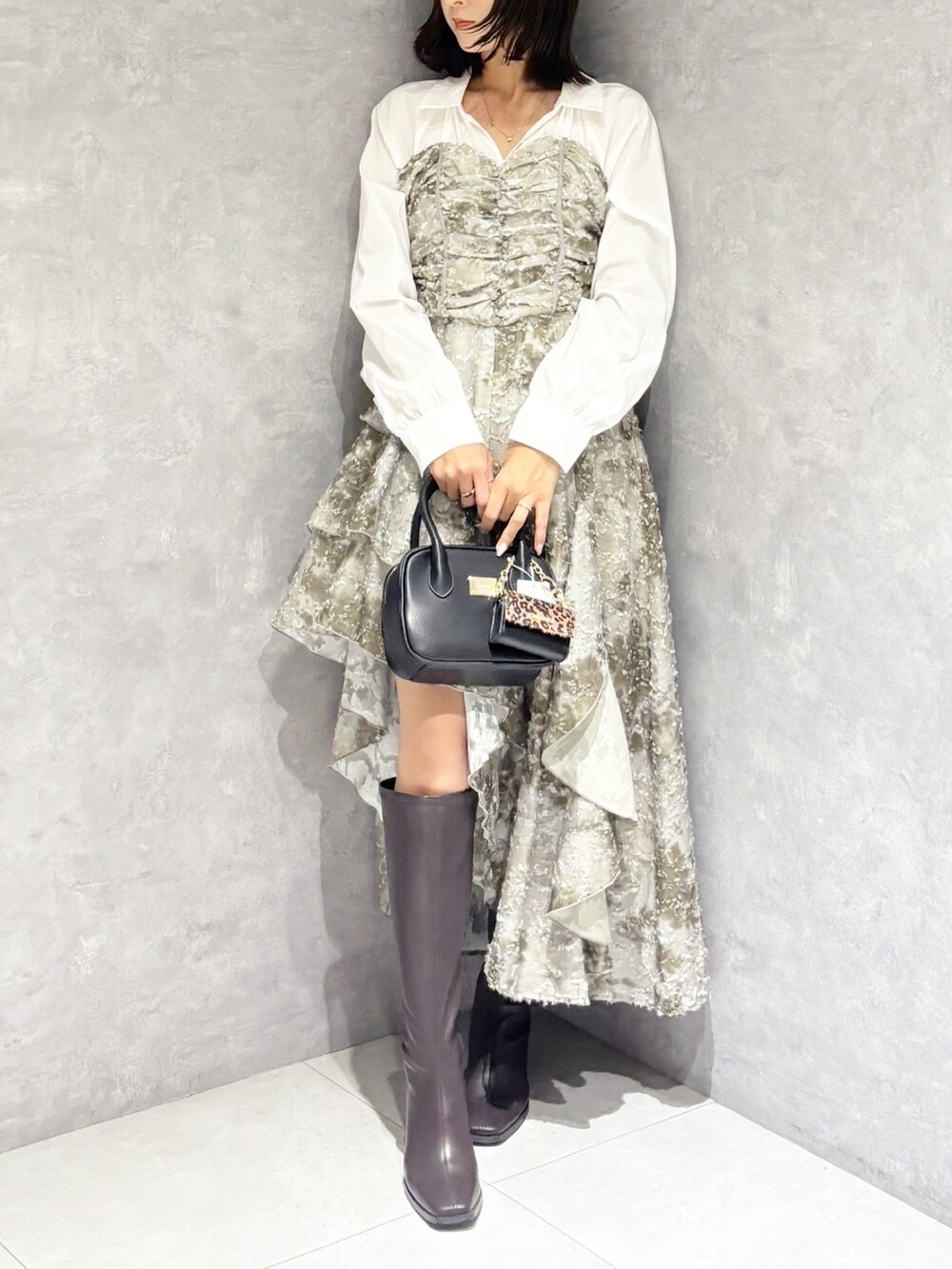ブラック系のハンドバッグ、ブラウン系のブーツ、グリーン系のワンピースを着用したレディースの秋コーディネートの4枚目の写真