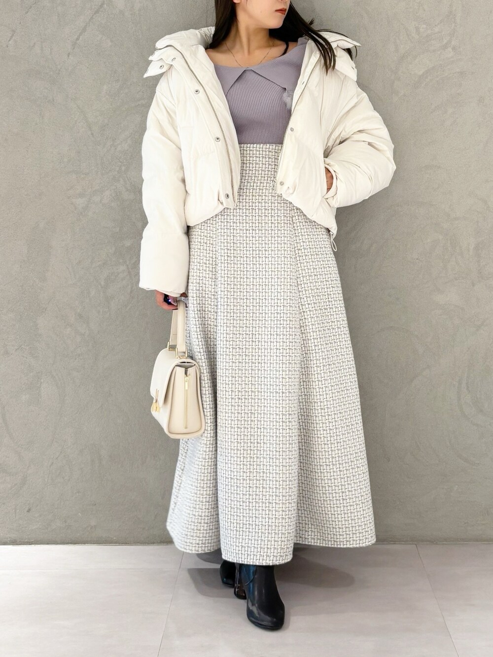 ホワイト系のスカート、ブラック系のブーツ、ホワイト系のハンドバッグを着用したレディースの冬コーディネートの9枚目の写真