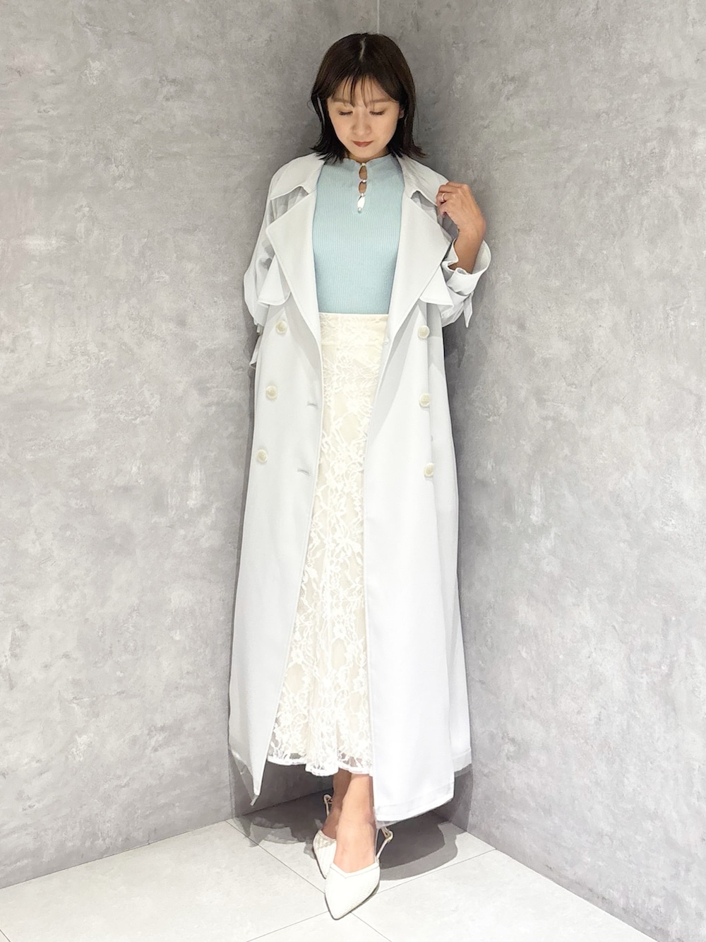 ホワイト系のスカート、ブルー系のトレンチコート、グリーン系のニット/セーターを着用したレディースの春コーディネートの6枚目の写真