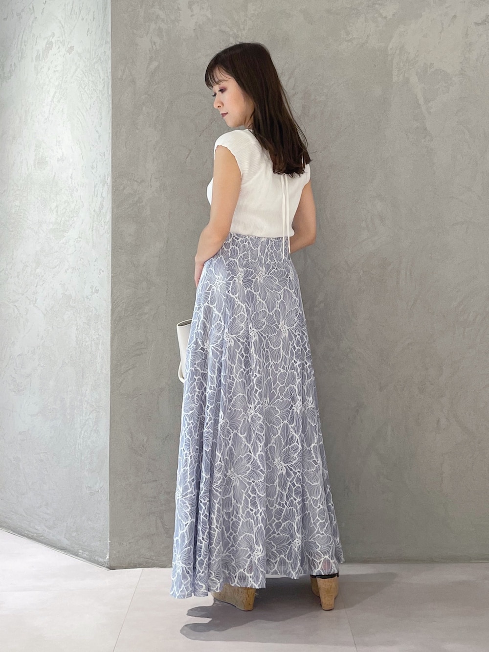 ブルー系のスカート、ブラック系のサンダル、ホワイト系のトートバッグを着用したレディースの夏コーディネートの2枚目の写真