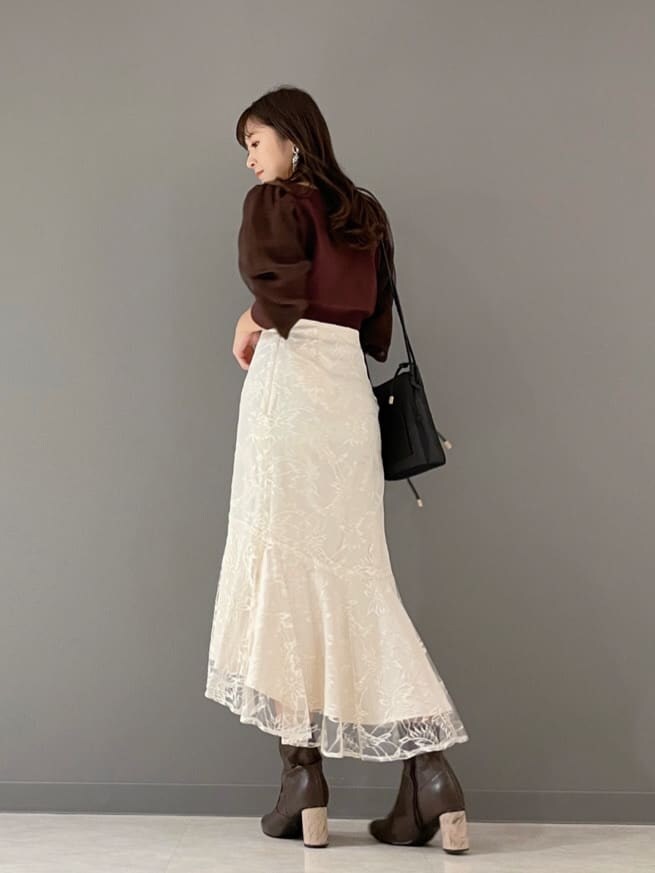 ベージュ系のショルダーバッグ、ブラウン系のカーディガン/ボレロ、ホワイト系のスカートを着用したレディースの冬コーディネートの6枚目の写真