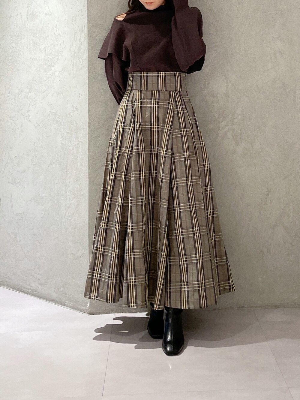 ベージュ系のスカート、ブラウン系のニット/セーター、ブラック系のブーツを着用したレディースの秋コーディネートの7枚目の写真