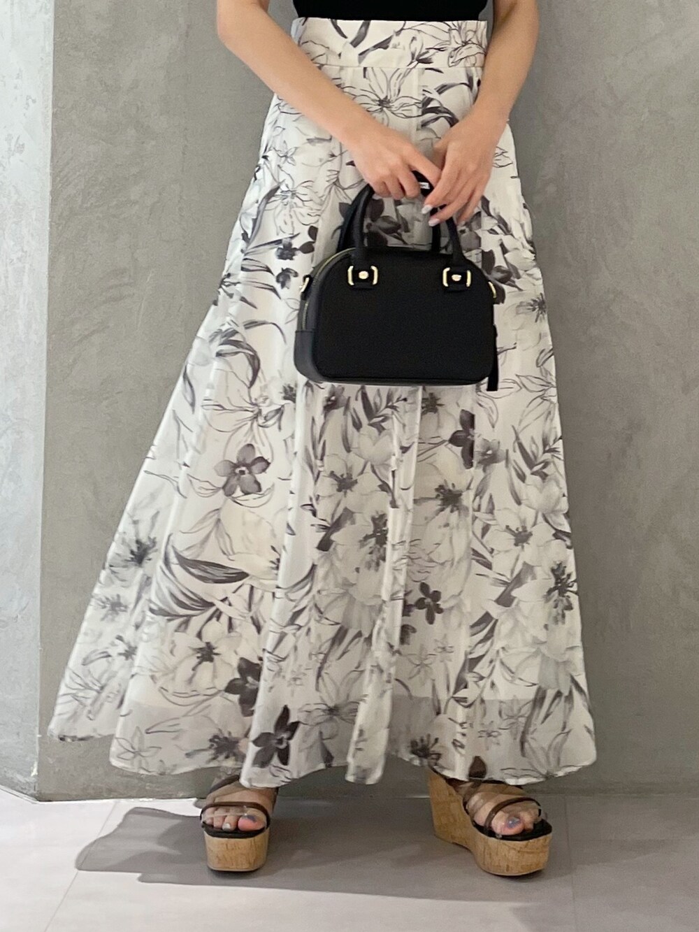 ホワイト系のボストンバッグ、ホワイト系のスカート、ブラック系のニット/セーターを着用したレディースの春コーディネートの4枚目の写真