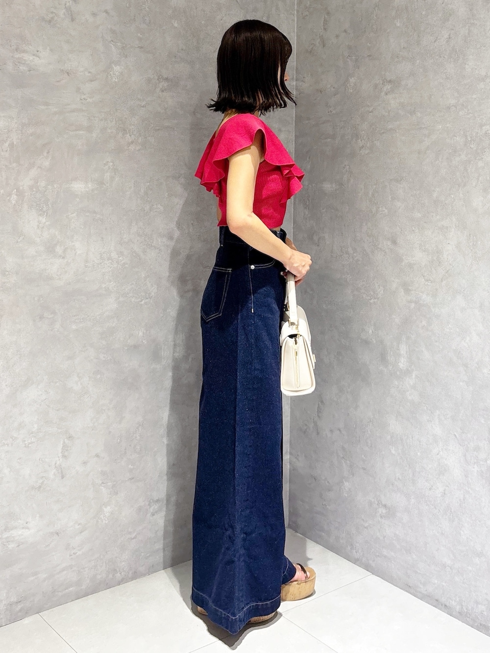 ブルー系のデニムパンツ、ブラウン系のサンダル、ホワイト系のハンドバッグを着用したレディースの夏コーディネートの3枚目の写真