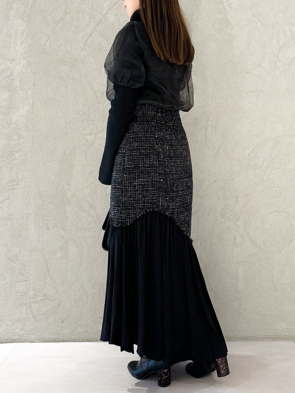 ブラック系のスカート、ブラック系のショルダーバッグ、ブラック系のブーツを着用したレディースの秋コーディネートの7枚目の写真