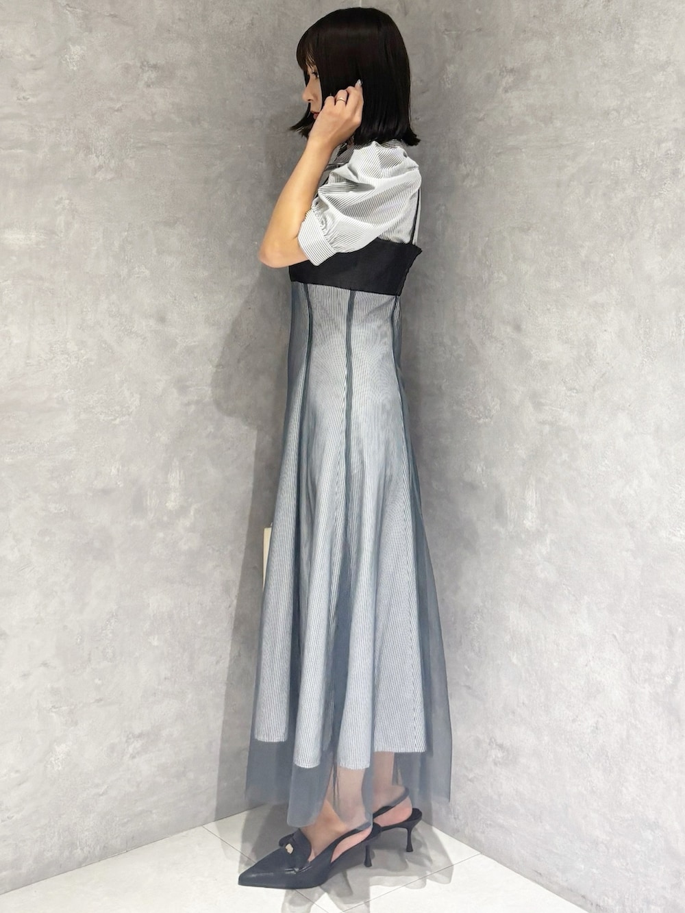 ブラック系のパンプス、ホワイト系のハンドバッグ、ブルー系のワンピースを着用したレディースの秋コーディネートの2枚目の写真