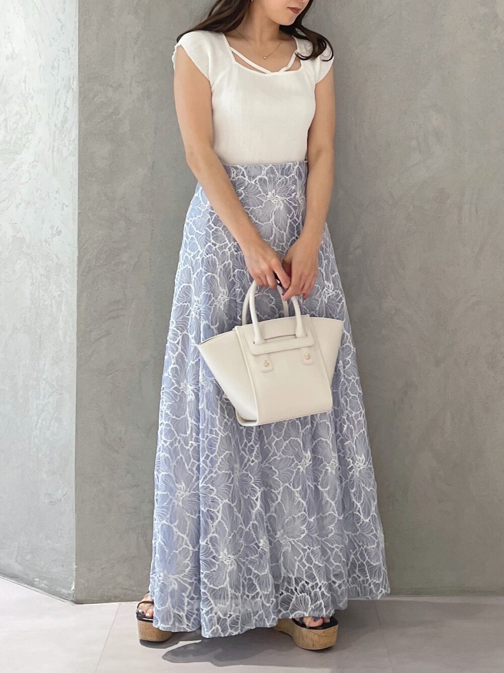 ブルー系のスカート、ブラック系のサンダル、ホワイト系のトートバッグを着用したレディースの夏コーディネートの3枚目の写真