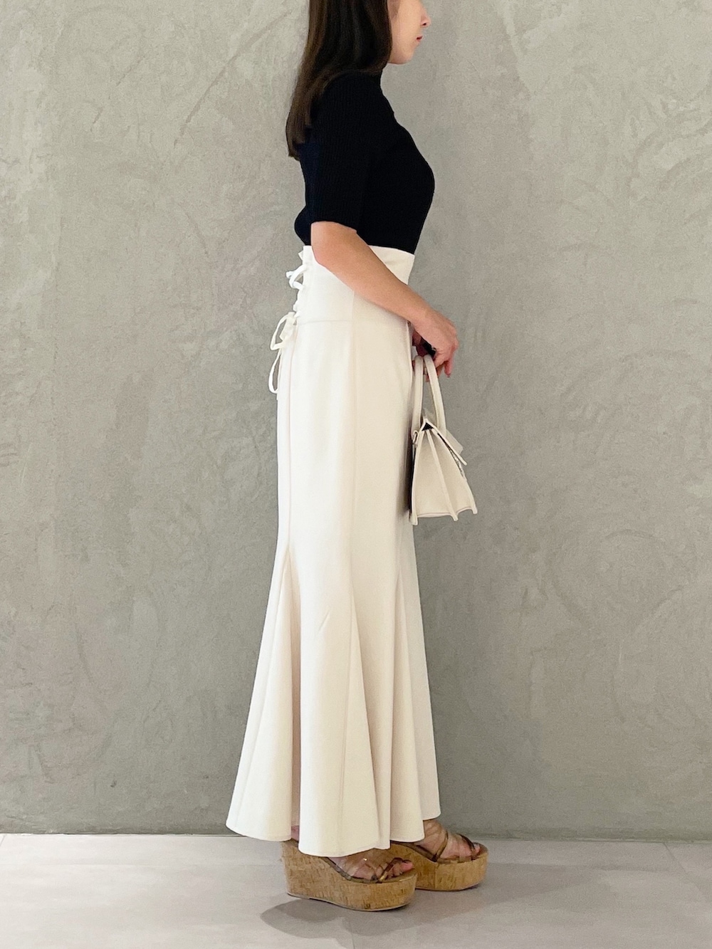 ピンク系のスカート、ブラウン系のサンダル、ベージュ系のショルダーバッグを着用したレディースの夏コーディネートの2枚目の写真