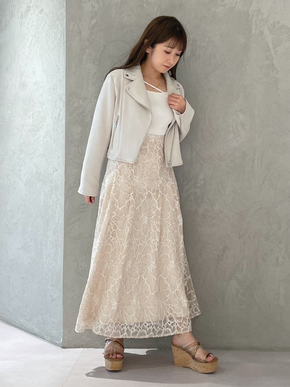 ブラウン系のサンダル、ホワイト系のニット/セーター、ホワイト系のライダースジャケットを着用したレディースの春コーディネートの2枚目の写真