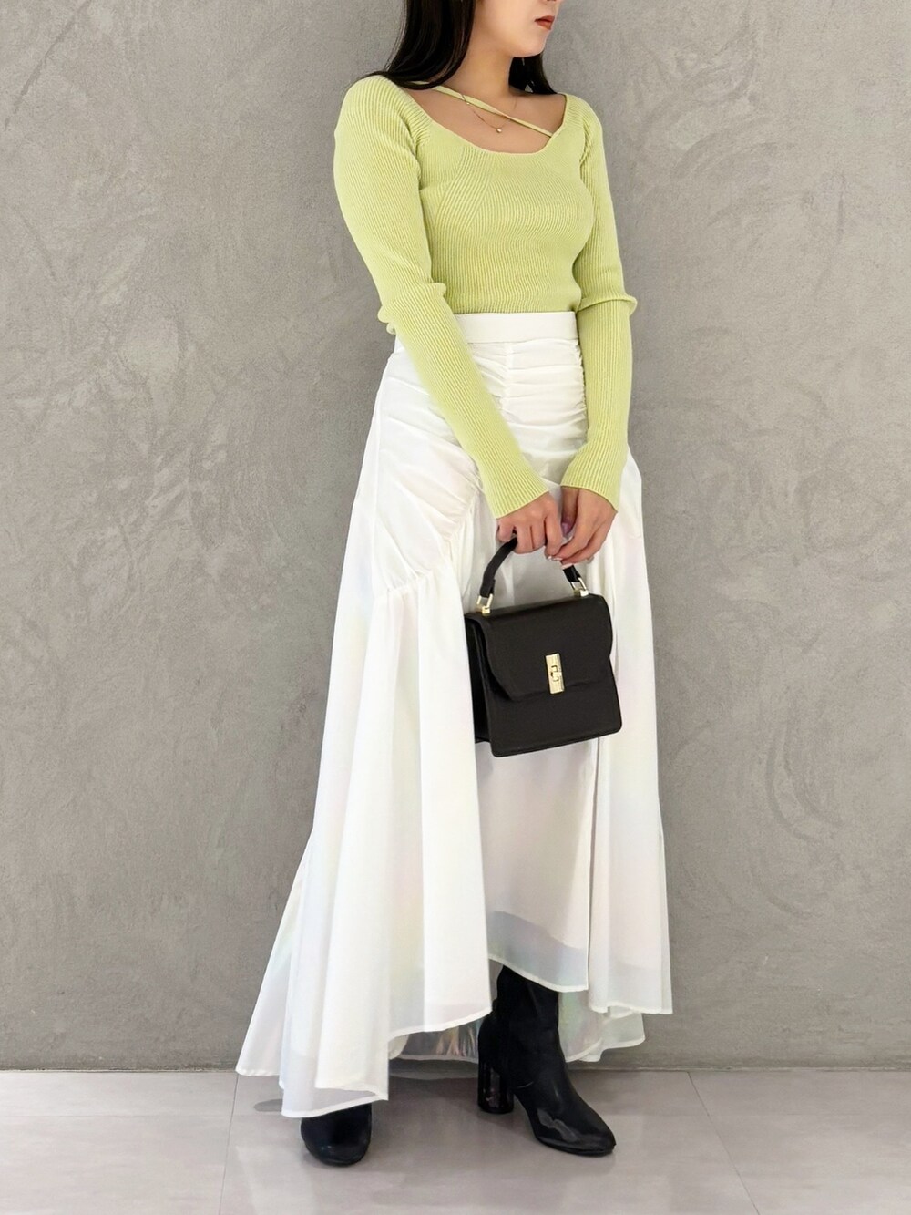 ホワイト系のスカート、ブラック系のブーツ、ブラウン系のハンドバッグを着用したレディースの冬コーディネートの4枚目の写真