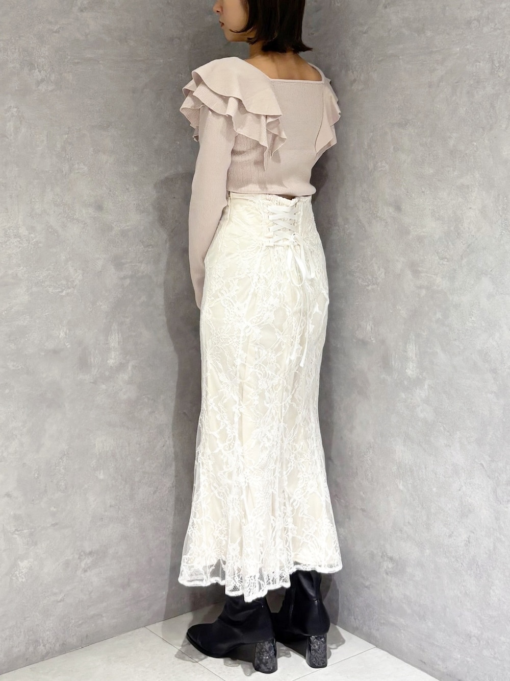 ホワイト系のスカート、ベージュ系のニット/セーター、ブラック系のブーツを着用したレディースの冬コーディネートの4枚目の写真