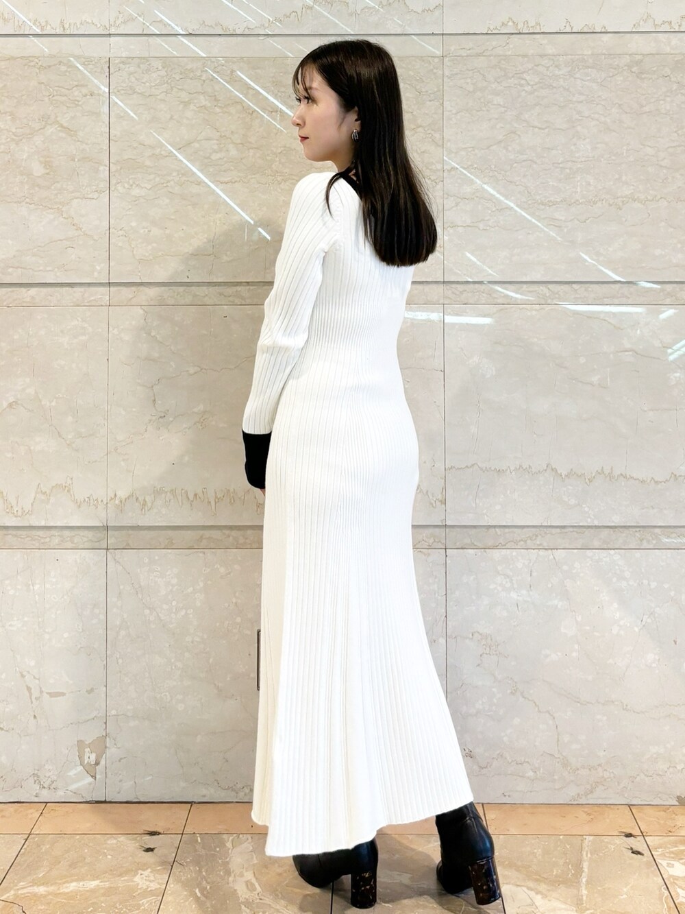 ホワイト系のワンピース、ブラック系のブーツを着用したレディースの冬コーディネートの3枚目の写真