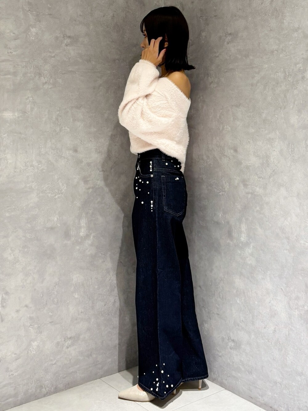 ブルー系のデニムパンツ、シルバー系のパンプス、ピンク系のニット/セーターを着用したレディースの秋コーディネートの2枚目の写真