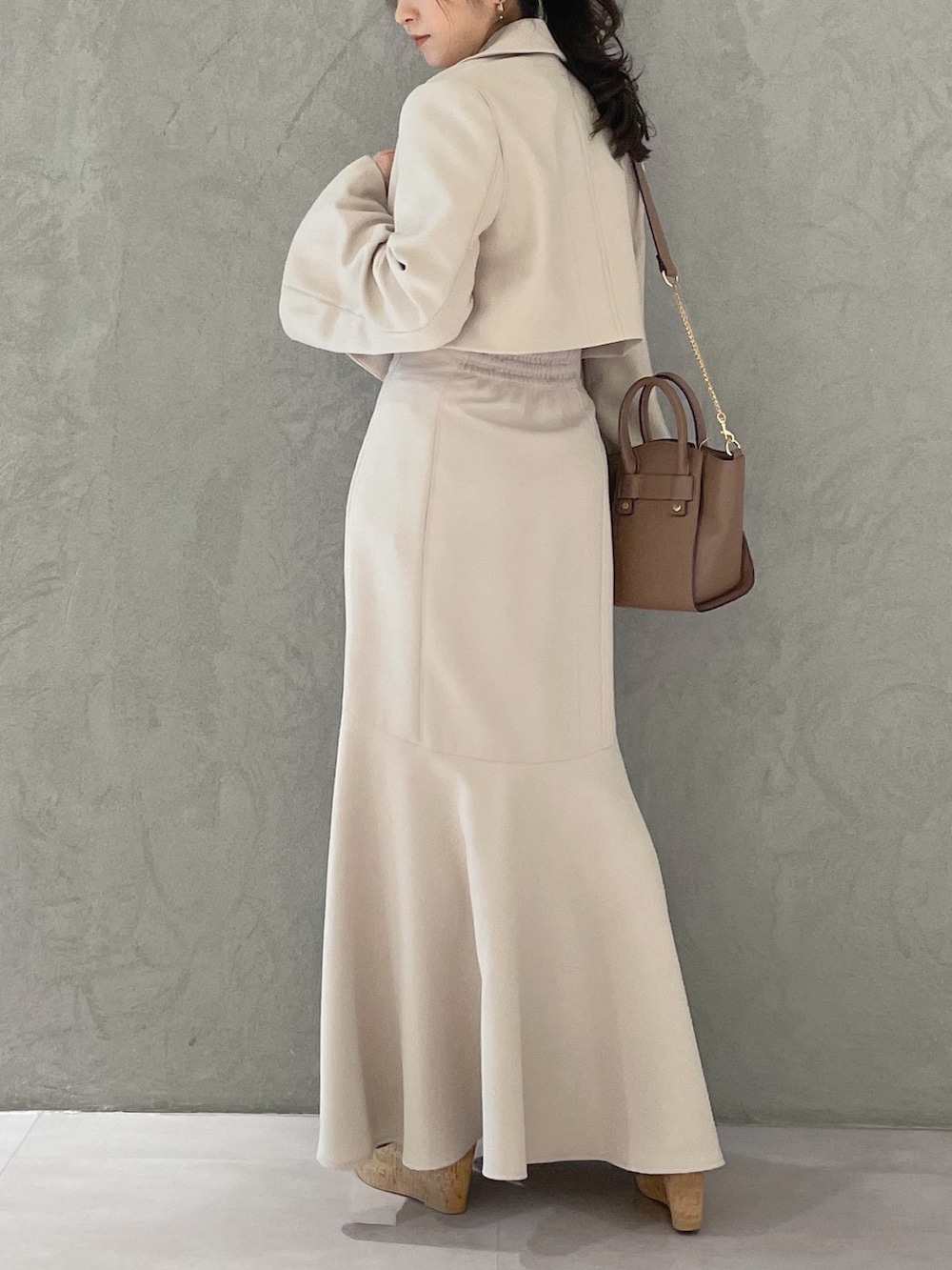 ブラック系のサンダル、ベージュ系のスカート、イエロー系のニット/セーターを着用したレディースの春コーディネートの2枚目の写真