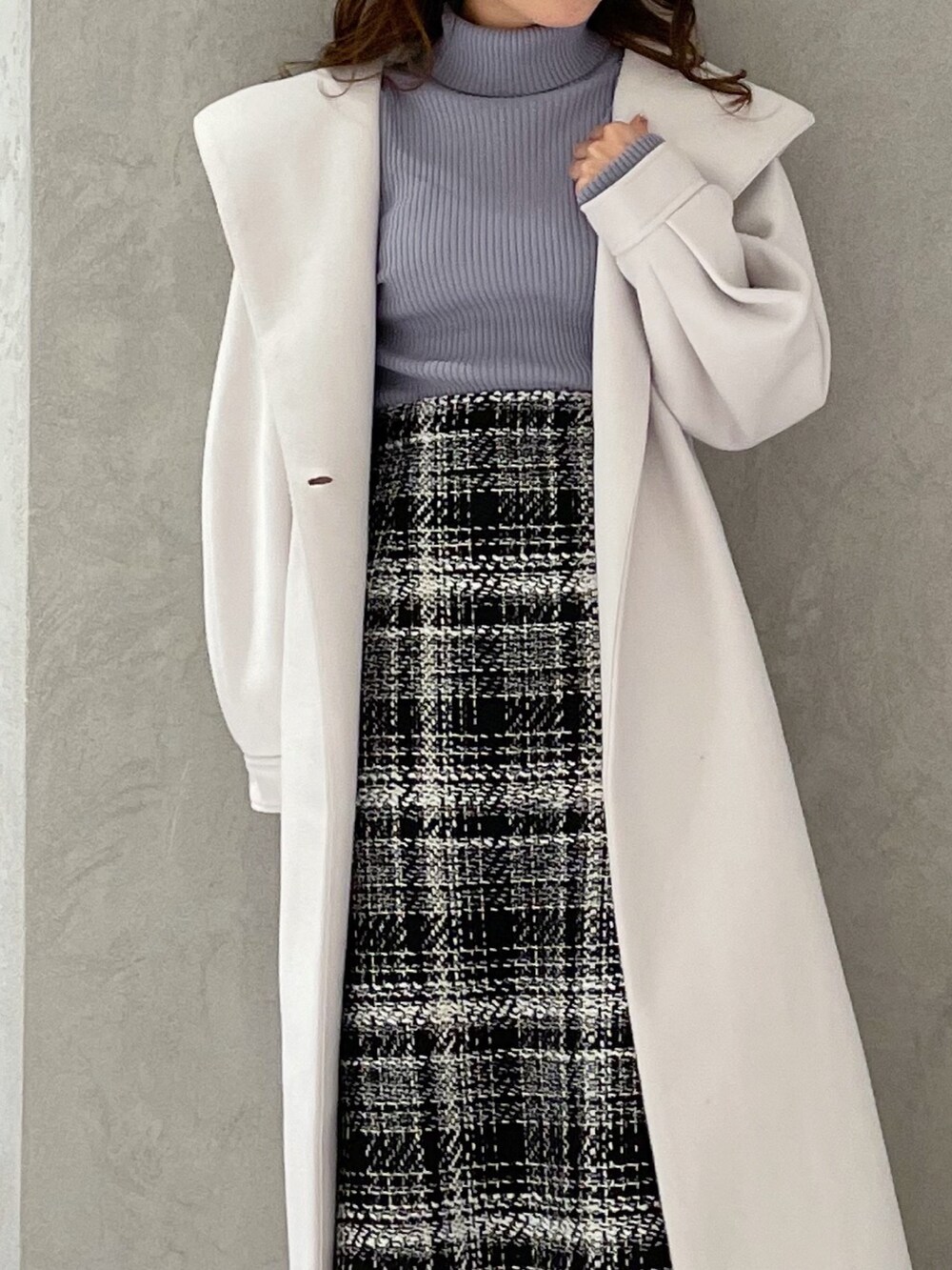 ブルー系のニット/セーター、ブラック系のスカート、ホワイト系のチェスターコートを着用したレディースの冬コーディネートの4枚目の写真