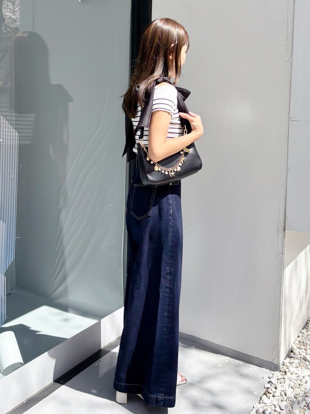 ブルー系のデニムパンツ、その他のニット/セーター、ホワイト系のサンダルを着用したレディースの夏コーディネートの2枚目の写真