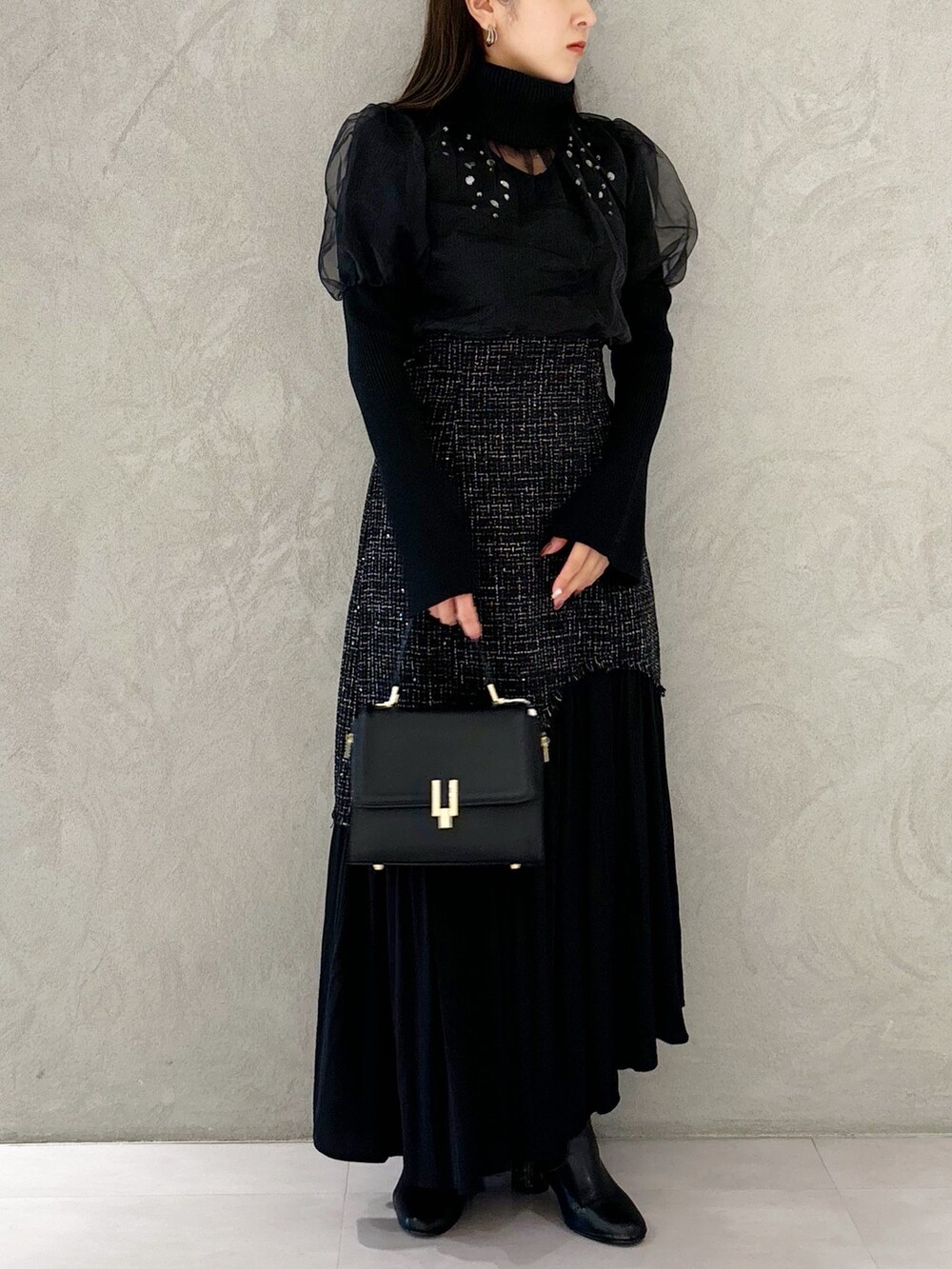 ブラック系のスカート、ブラック系のショルダーバッグ、ブラック系のブーツを着用したレディースの秋コーディネートの5枚目の写真