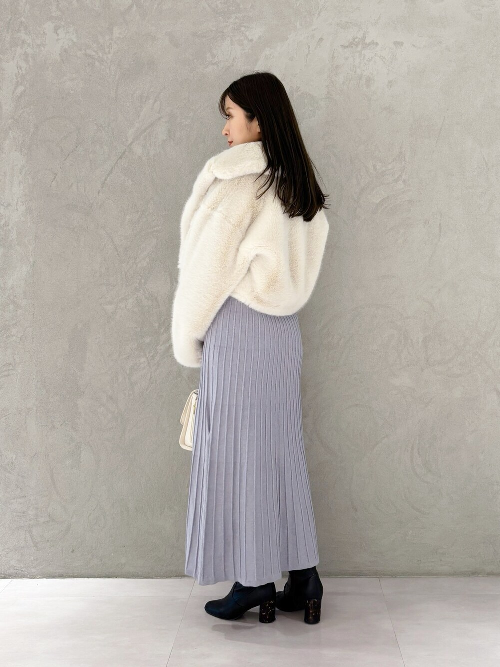 ブルー系のワンピース、ブラック系のブーツ、ホワイト系のその他アウターを着用したレディースの冬コーディネートの6枚目の写真