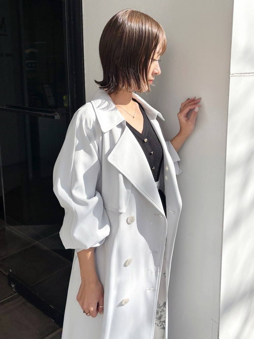 ブラック系のワンピース、ブラウン系のパンプス、ブルー系のトレンチコートを着用したレディースの春コーディネートの2枚目の写真