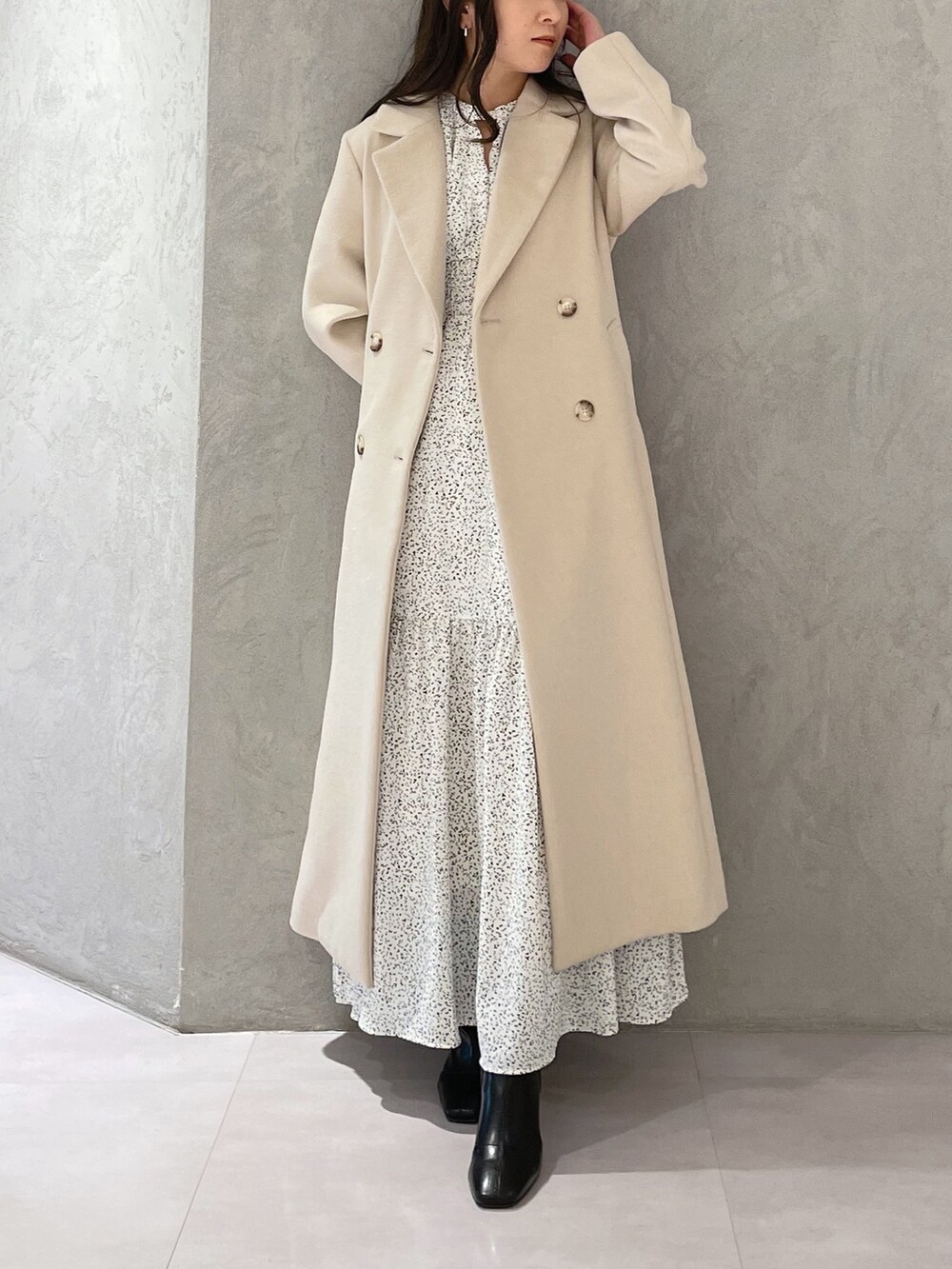 ホワイト系のワンピース、ベージュ系のチェスターコート、ブラック系のブーツを着用したレディースの秋コーディネートの7枚目の写真