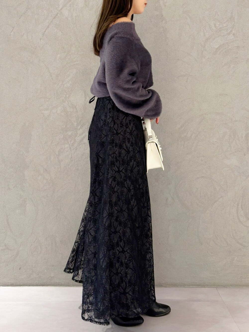 ブラック系のスカート、ブラック系のブーツ、ホワイト系のショルダーバッグを着用したレディースの冬コーディネートの4枚目の写真