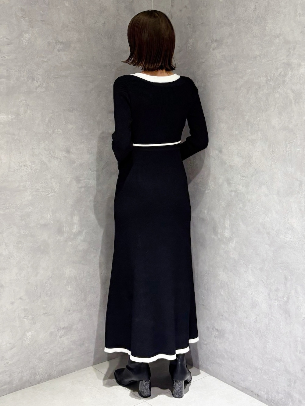 ブラック系のワンピース、ブラック系のハンドバッグ、ブラック系のブーツを着用したレディースの冬コーディネートの3枚目の写真