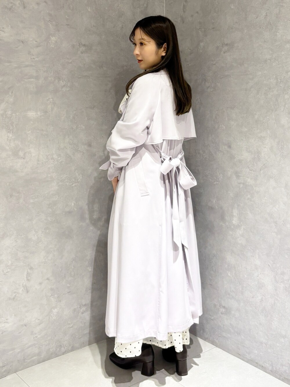 ホワイト系のワンピース、パープル系のトレンチコート、ブラウン系のハンドバッグを着用したレディースの冬コーディネートの6枚目の写真