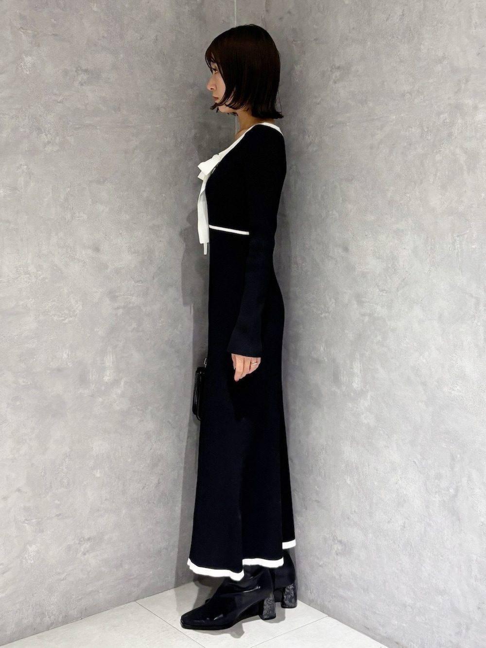 ブラック系のワンピース、ブラック系のハンドバッグ、ブラック系のブーツを着用したレディースの冬コーディネートの2枚目の写真