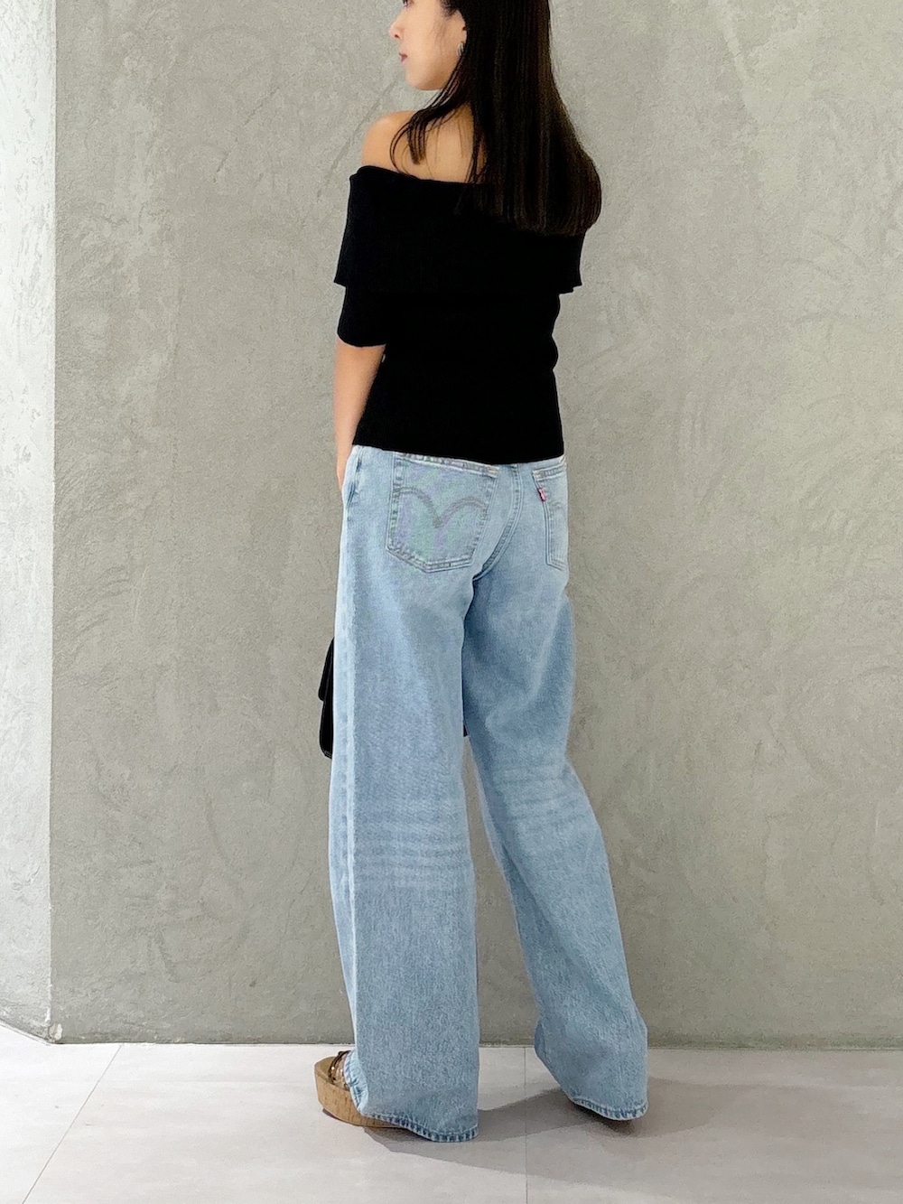 ブラック系のニット/セーター、ブラウン系のサンダル、ブラック系のショルダーバッグを着用したレディースの夏コーディネートの3枚目の写真