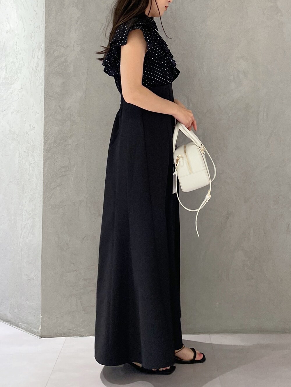 ブラック系のワンピース、ホワイト系のボストンバッグ、ブラック系のサンダルを着用したレディースの春コーディネートの7枚目の写真