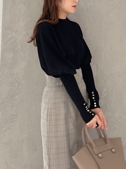 ブラウン系のハンドバッグ、グレー系のスカート、ブラック系のニット/セーターを着用したレディースの秋コーディネートの2枚目の写真