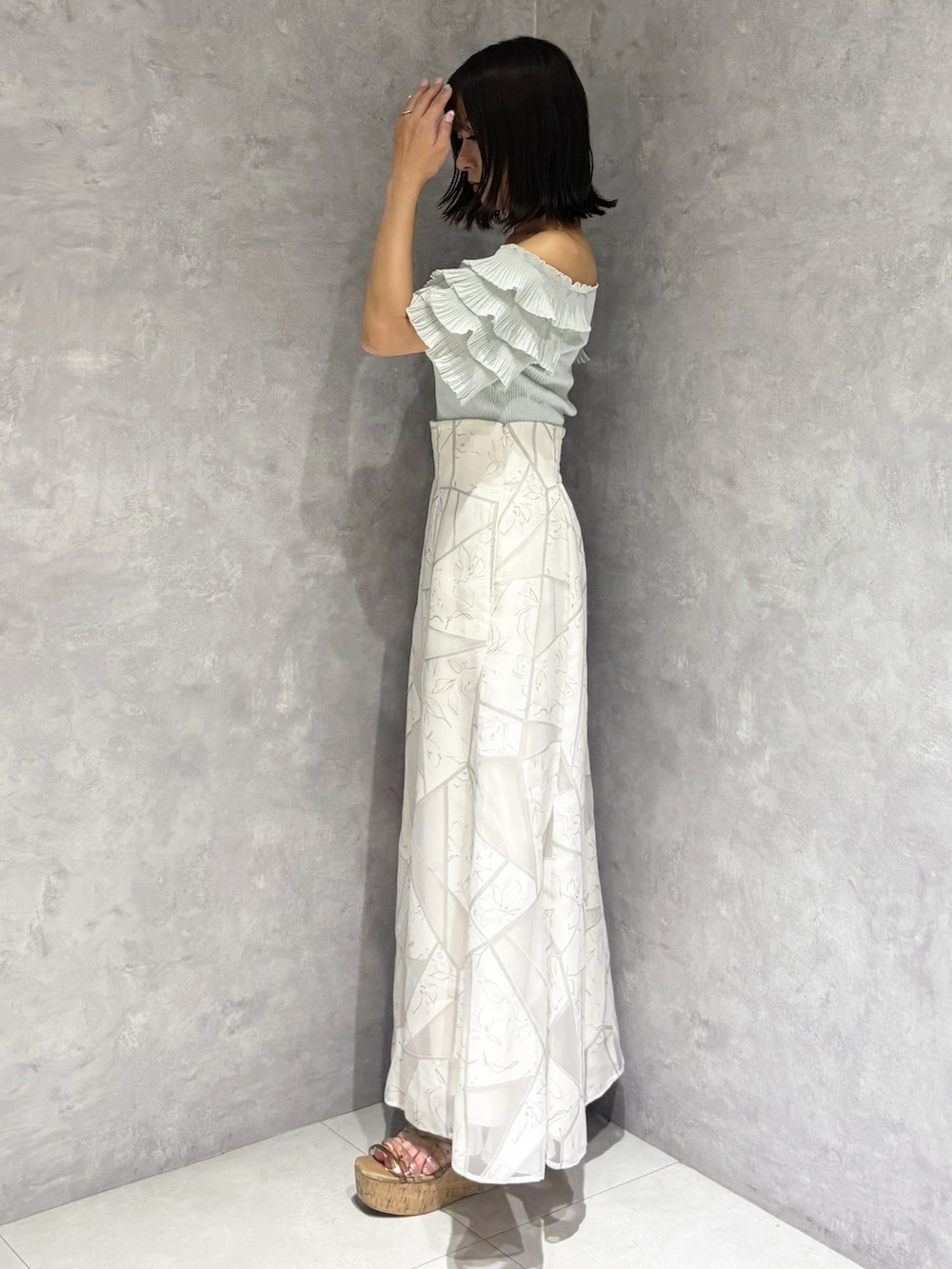 ホワイト系のスカート、グリーン系のニット/セーター、ブラウン系のサンダルを着用したレディースの夏コーディネートの2枚目の写真