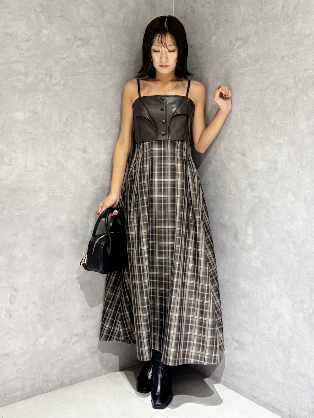 ブラウン系のワンピース、ブラック系のブーツ、ブラック系のハンドバッグを着用したレディースの秋コーディネートの3枚目の写真