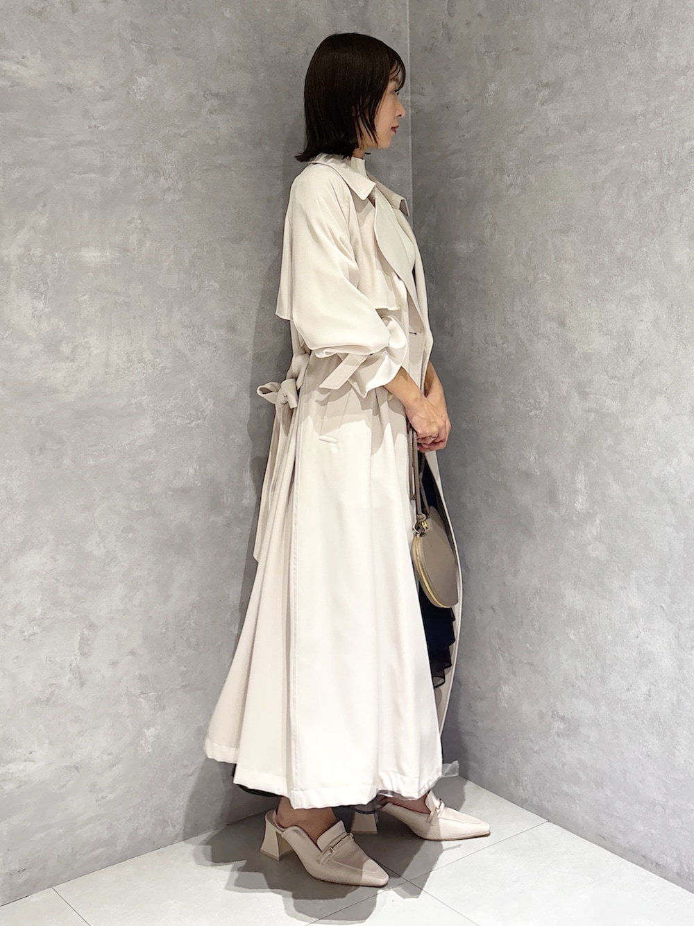 ブルー系のスカート、ホワイト系のニット/セーター、ホワイト系のパンプスを着用したレディースの春コーディネートの2枚目の写真