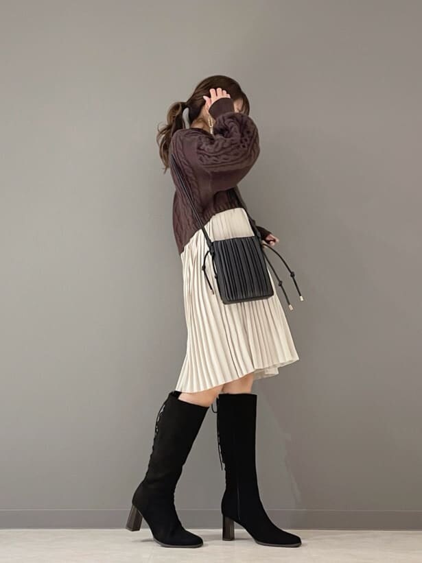 ベージュ系のショルダーバッグ、ブラウン系のワンピース、ゴールド系のピアス（両耳用）を着用したレディースの冬コーディネートの3枚目の写真