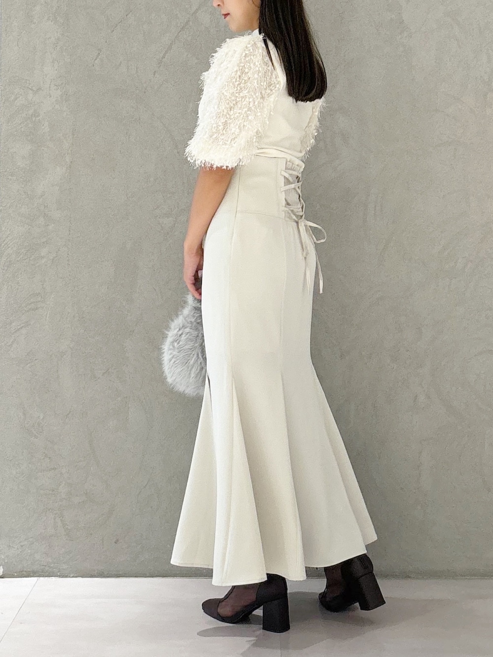 ブラウン系のブーツ、グレー系のハンドバッグ、ホワイト系のスカートを着用したレディースの夏コーディネートの2枚目の写真