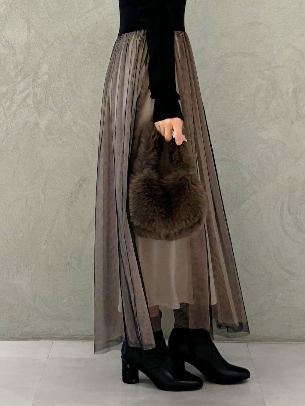 ブラック系のワンピース、ブラック系のブーツ、ブラウン系のハンドバッグを着用したレディースの秋コーディネートの9枚目の写真