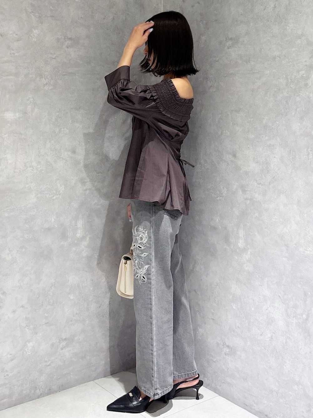 ホワイト系のハンドバッグ、ブラック系のパンプス、グレー系のデニムパンツを着用したレディースの夏コーディネートの6枚目の写真